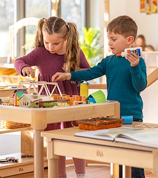 A teacher and a child with SEND use an acticvity tray-table for sensory play
