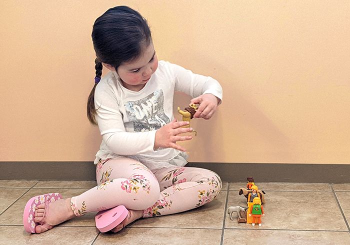 A young child sitting on the floor with her legs angled to one side