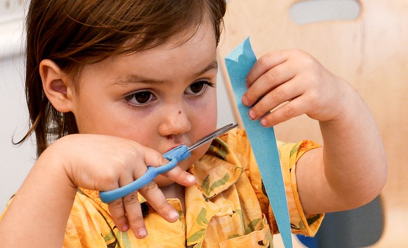 A small child snipping a ribbon with scissors